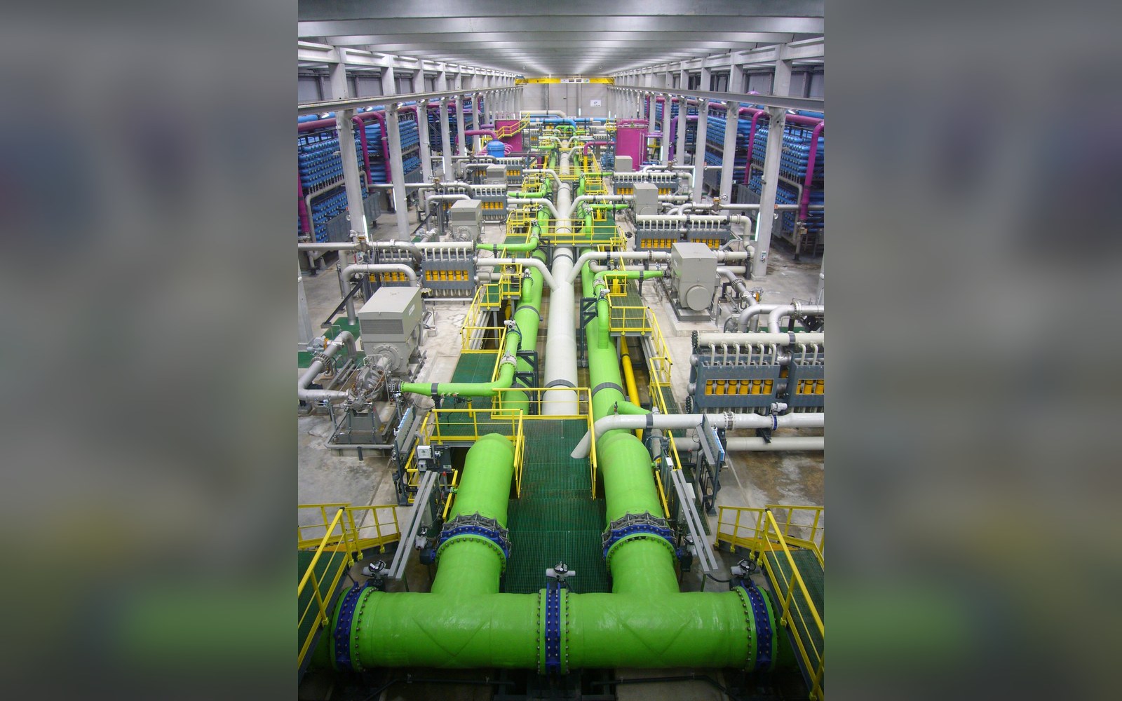 Rows of white reverse-osmosis pressure vessels inside a desalination hall